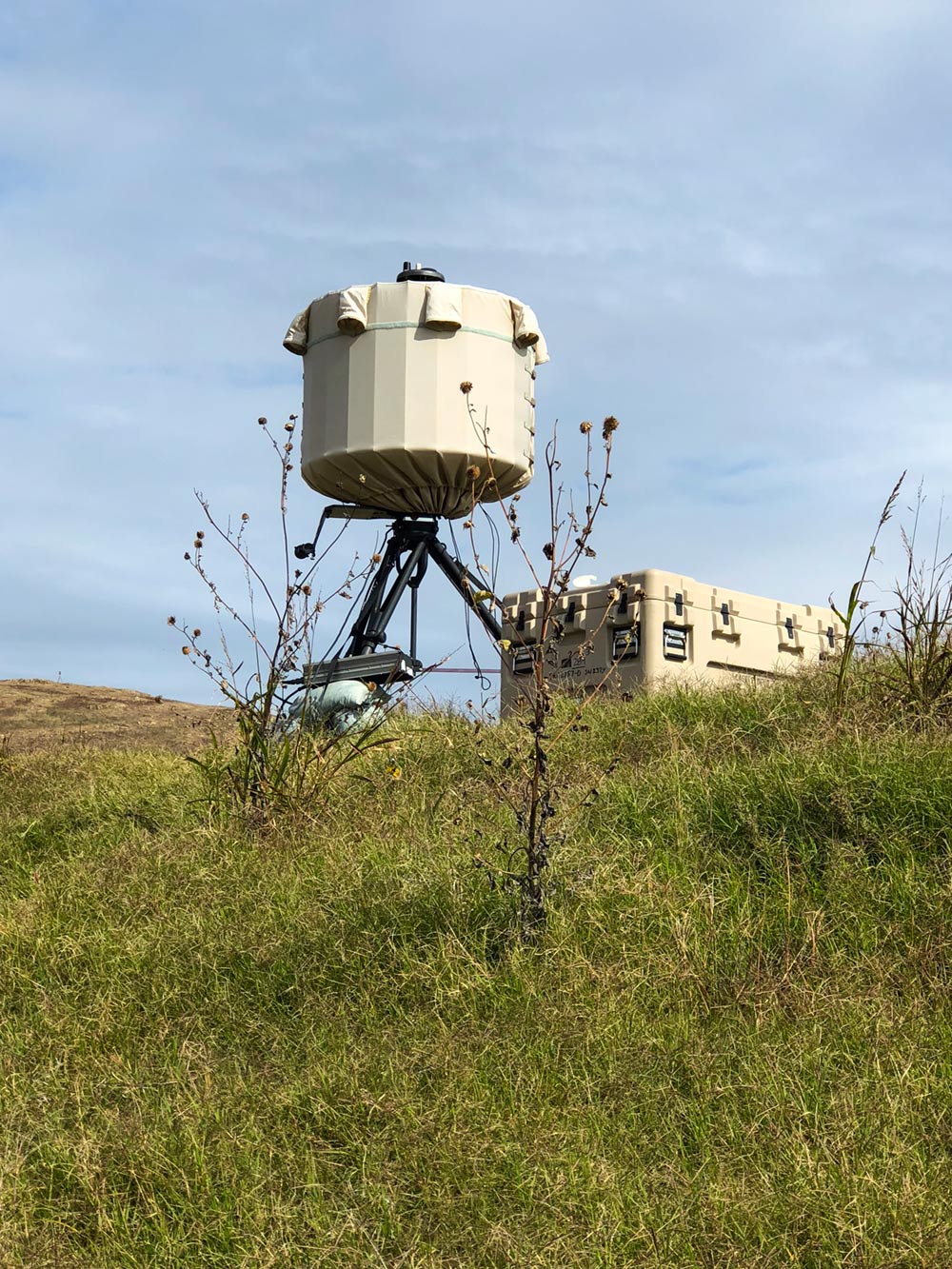 SRC's AN/TPQ-49 radar on a grassy hill with an equipment box